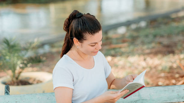 istock Woman reading a book outdoors 1485434531