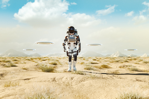 Astronaut with flying UFOs walking in the desert. 3D generated image.