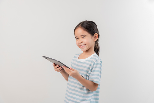 smiling little girl stiiting and holding a tablet
