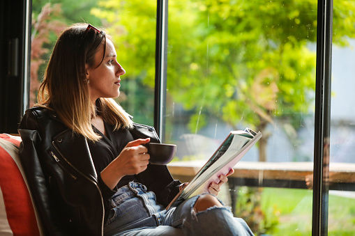 Young Business Woman Having A Coffee Break And Reading Magazine Having A Nice Day.