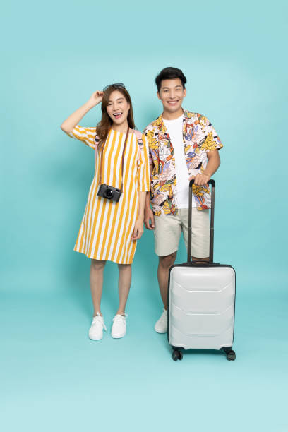 緑の背景にスーツケースバッグを持つ夏の衣装を着たアジアの夫婦 - travel suitcase hawaiian shirt people traveling ストックフォトと画像