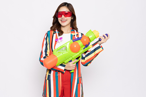 Young Asian woman in colorful striped shirt suit summer outfits holding water guns plastic for Songkran festival in Thailand isolated on white background