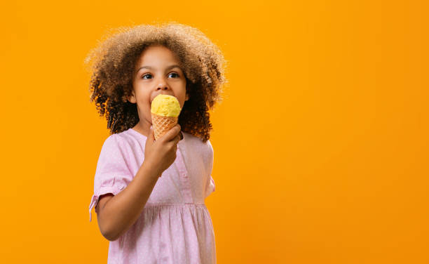 a Black child eats ice cream in a waffle cone at a summer day