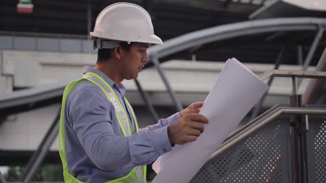 Male Civil engineer with hard hat looking and checking progress of Sky Train project.