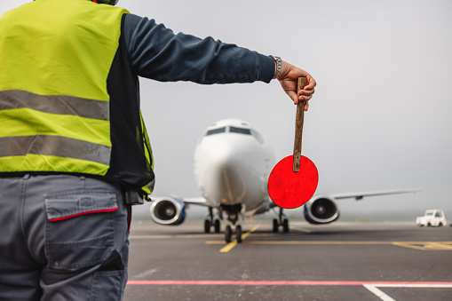 Unrecognizable air traffic controller coordinating aircraft traffic in the airfield.