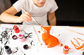 a little girl paints a toy fox made of clay. DIY concept