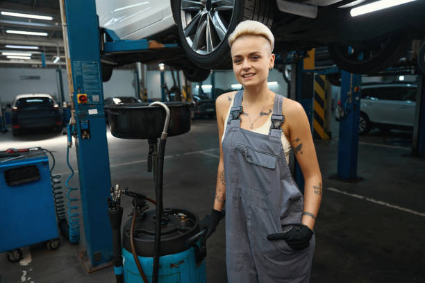 istock Pretty car mechanic stands with a device for draining oil 1485454102