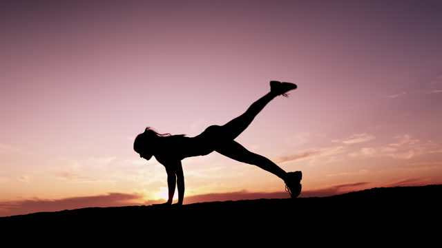 Silhouette, sunset and yoga with a woman outdoor in nature against a colorful sky background. Fitness, wellness and zen with a female yogi practicing pilates for mental health, peace or balance