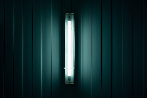 Fluorescent long tube lamp mounted on ceiling or wall of building. Electricity and energy saving concept.