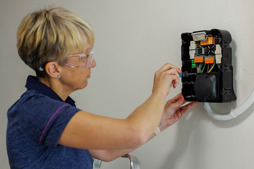 Certified female electrician installing home EV charger.