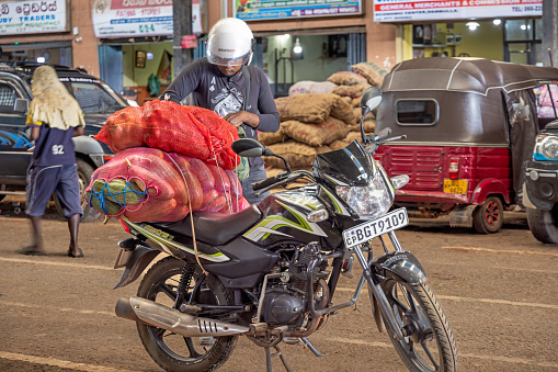 Dambulla, Central Province, Sri Lanka - March 1th 2023: Man is loading his motorcycle with his purchases at the large indoor green market