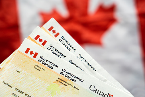 Canada Government Tax Refund Cheques with Canadian flag in the background, benefit cheque Canadian Government