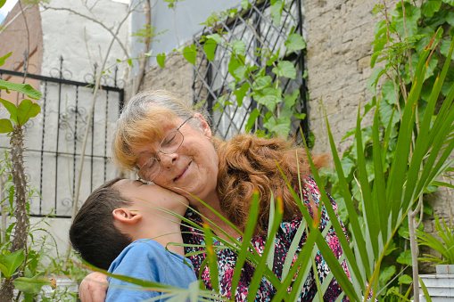 grandson lovingly kisses his grandmother's cheek while gardening from home