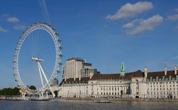 The London Eye and County Hall building on the south bank of the River Thames in Lambeth, London, UK. London, UK - September 14, 2022: The London Eye and County Hall building under a blue sky on the River Thames in London, UK. london county hall stock pictures, royalty-free photos & images