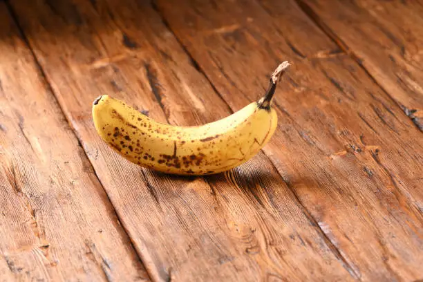 Not fresh banana on a brown wooden table.