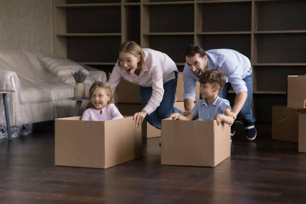 padres felices y emocionados e hijos que celebran mudarse a un nuevo hogar - moving house physical activity real estate couple fotografías e imágenes de stock