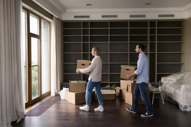 istock Young millennial married couple carrying boxes into empty living room 1485496788