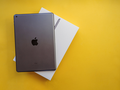 Lleida, Spain - February 28, 2023 : Studio photo of the new gray Apple iPad, logo from rear view. Isolated on yellow background. Illustrative editorial content.