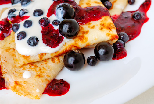 Thin pancakes with sweet currant and berry sauce close-up