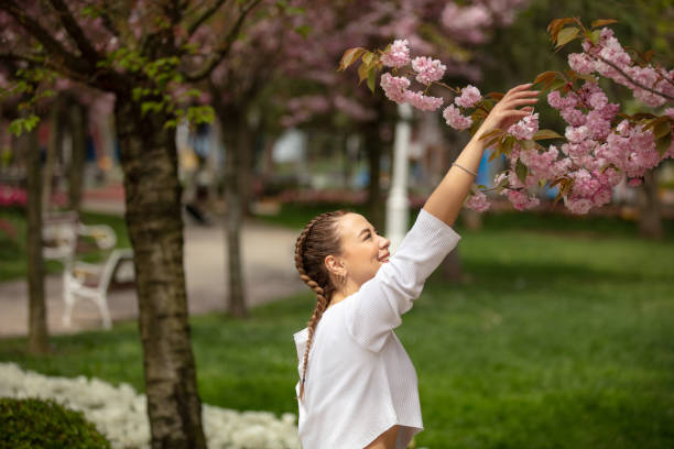 istock Young woman is touching Cherry Blossom tree at public park. 1485503956