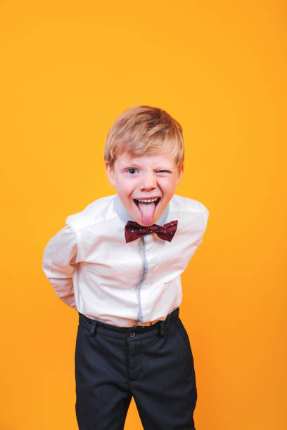 黄色の背景にいたずらな金髪の少年が舌を突き出す - preschooler caucasian one person part of ストックフォトと画像