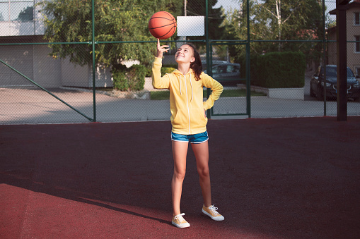 Portrait of a teenage girl practicing basketball.