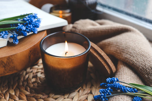 istock Burning candle and spring flowers on the windowsill in the home interior 1485518188