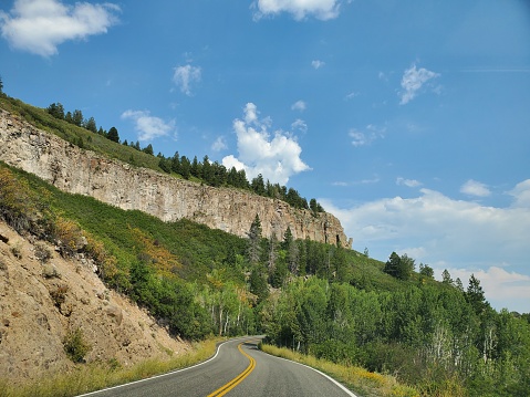 This is a photograph taken on a mobile phone outdoors of a winding road through a the scenic landscape in Curecanti National Recreation Area on the north rim of Black Canyon of the Gunnison National Park in Colorado USA in during the summer of 2020