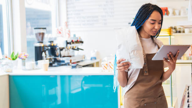 istock African American woman looking at tablet screen, holding package with coffee beans 1485536148