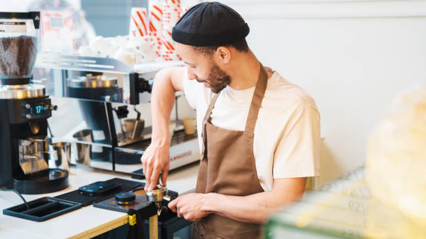 istock Male barista using tamper at espresso machine in coffee shop 1485536220