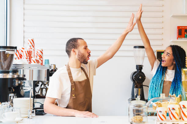 istock Two workers giving high five celebrating successful business cafe while standing in cafe 1485538317