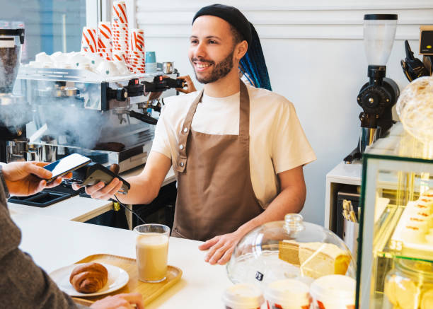 istock Smiling male barista accepting payment while using card swipe machine 1485539657