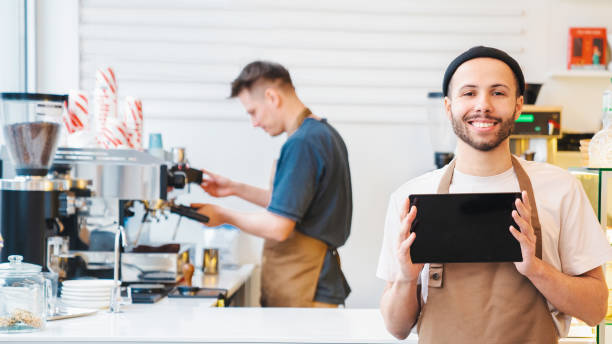 istock Smiling male barista showing digital tablet screen, copy space 1485539744