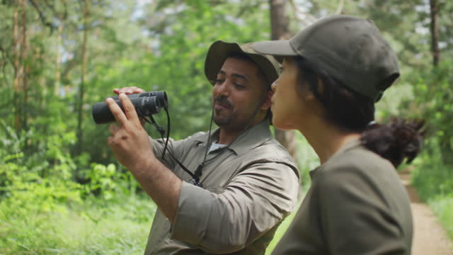 Diverse Forest Rangers Looking at Birds through Binoculars