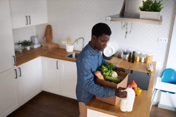 istock Black man unpacking fresh groceries in kitchen interior 1485541763