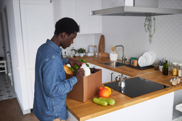 istock Side view black man unpacking fresh groceries in kitchen interior 1485541769
