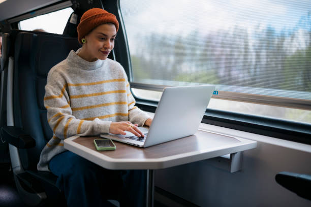 Beautiful young woman working on laptop in train