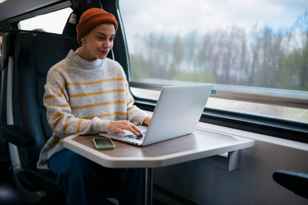 Beautiful young woman working on laptop in train stock photo