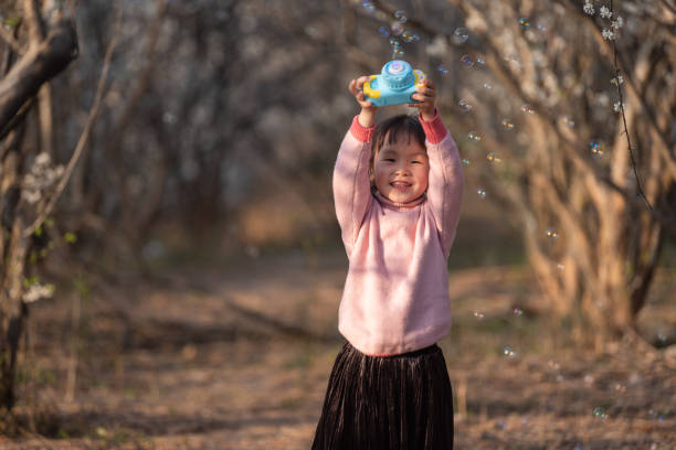 istock A little girl blowing bubbles with a bubble machine in the forest 1485546483