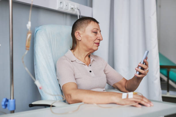 istock Side view mature woman using smartphone during IV drip treatment 1485546502