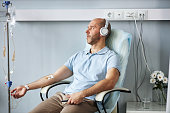 Man wearing headphones and listening to music during IV drip treatment in clinic