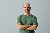 Bald man smiling at camera standing with arms crossed