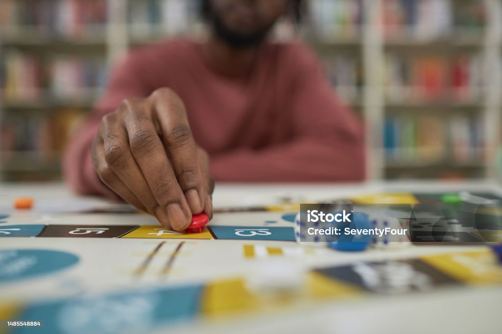 Closeup of black man playing board game Closeup of black man playing board game with focus on male hand moving game piece, copy space Board Game Stock Photo