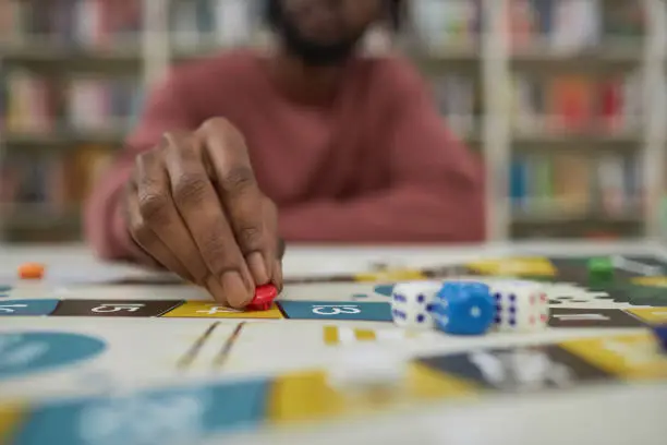 Closeup of black man playing board game with focus on male hand moving game piece, copy space
