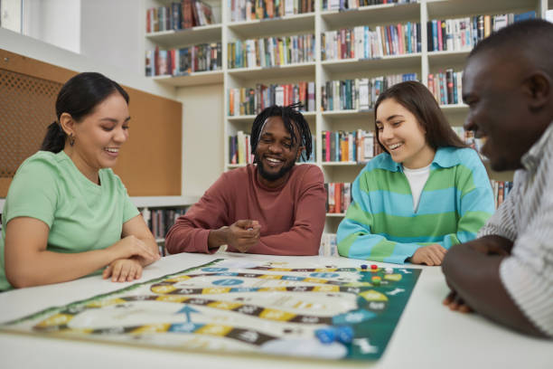 istock Group of cheerful young people playing board games together in library 1485548948