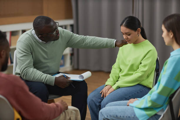 Black man as male psychologist comforting teenage girl in therapy session