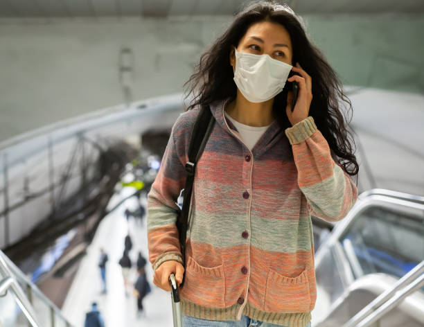 istock Woman in face mask with backpack walking in subway beside escolator 1485566631