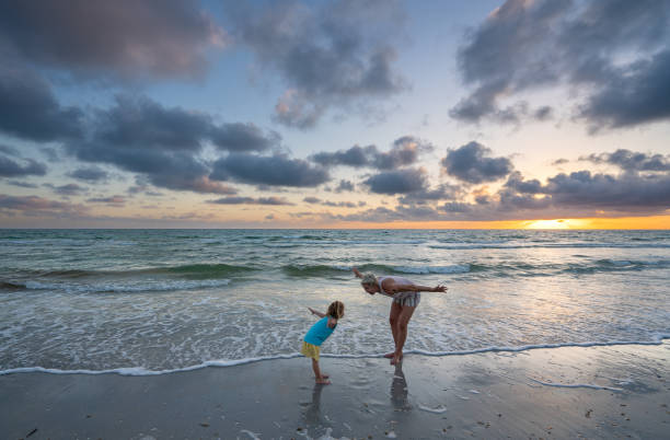 Mother and Daughter Playing During a Vibrant Sunset at Treasure Island Beach on the Gulf Coast of Florida USA Mother and daughter playing during a vibrant sunset at Treasure Island Beach on the Gulf Coast of Florida USA clearwater stock pictures, royalty-free photos & images