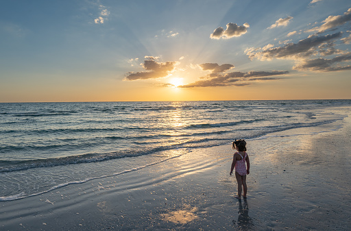 Child playing during a vibrant sunset at Treasure Island Beach on the Gulf Coast of Florida USA