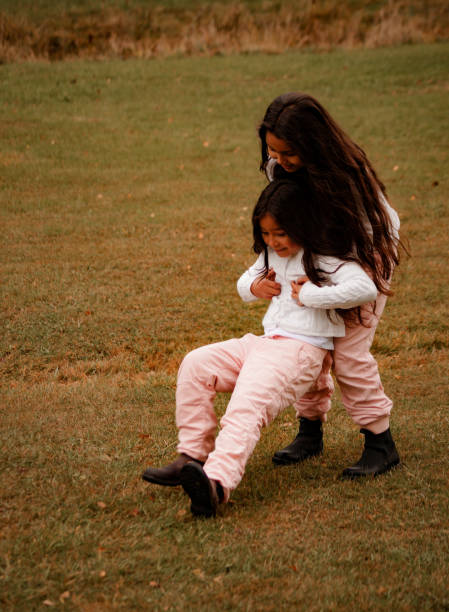 две сестры играют на поле днем - sibling sweden family smiling стоковые фото и изображения